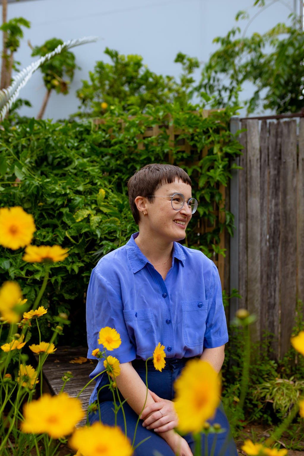 Chauncey Sjostedt sitting outdoors in a garden among yellow flowers