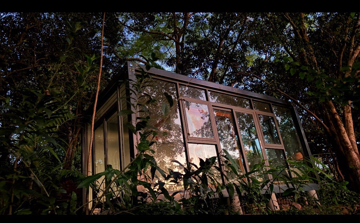 Modern glass portable office pod glowing warm at dusk in Australian bushland setting